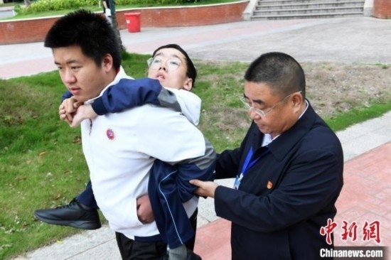 朱金祥背著鐘華強(qiáng)去教室上課的路上，也經(jīng)常碰到值班的校領(lǐng)導(dǎo)和老師前來搭把手。 卓忠偉 攝