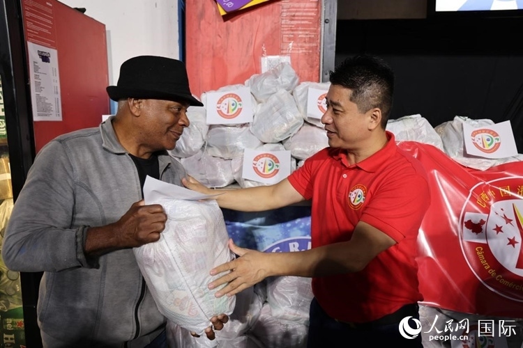 巴西中國浙江商會會長鄭俠茂向社區(qū)居民轉(zhuǎn)交捐贈物資。人民網(wǎng)記者 時元皓攝