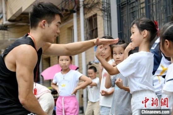 圖為大學(xué)生志愿者在組織孩子們參加體育健身活動(dòng)。廖光福 攝