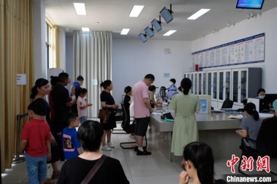 圖為在戶籍辦證廳內(nèi)排隊等待的家長和孩子。劉俊聰 攝