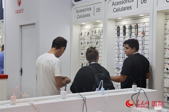 幾名參觀者在一個(gè)展臺(tái)前了解手機(jī)配件。（人民網(wǎng)記者 時(shí)元皓攝）