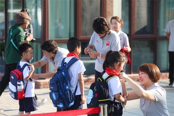 8月30日，雄安史家胡同小學(xué)學(xué)生體驗(yàn)學(xué)校生活。老師為學(xué)生佩戴?；?。