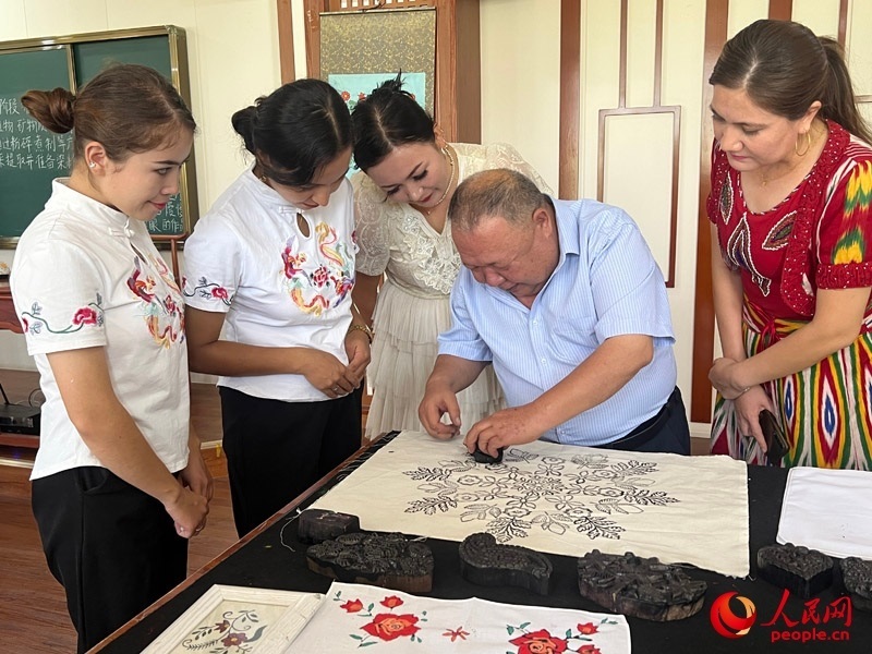 國家級非物質(zhì)文化遺產(chǎn)模戳印花布技藝傳承人吾吉阿西木?吾舒爾展示模戳印花布的制作過程。人民網(wǎng)記者 常雪梅攝