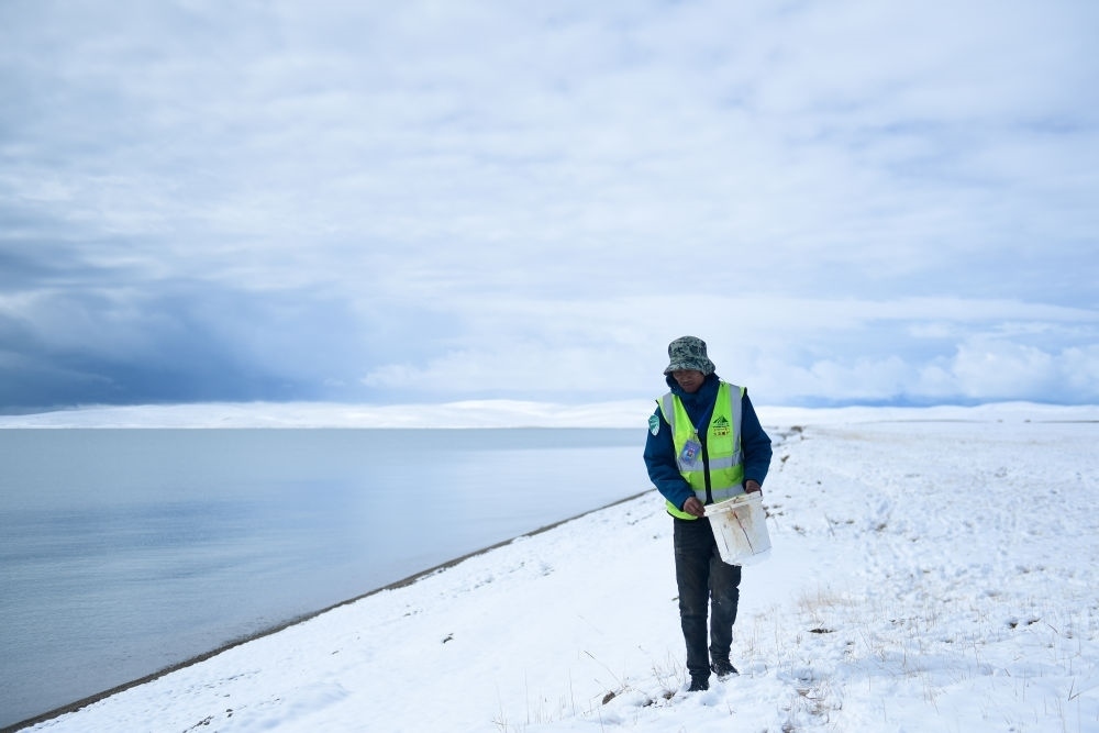 2021年10月20日，在青海省果洛藏族自治州瑪多縣扎陵湖鄉(xiāng)勒那村，三江源國家公園黃河源園區(qū)生態(tài)管護員在扎陵湖邊撿拾垃圾。新華社記者 張龍 攝