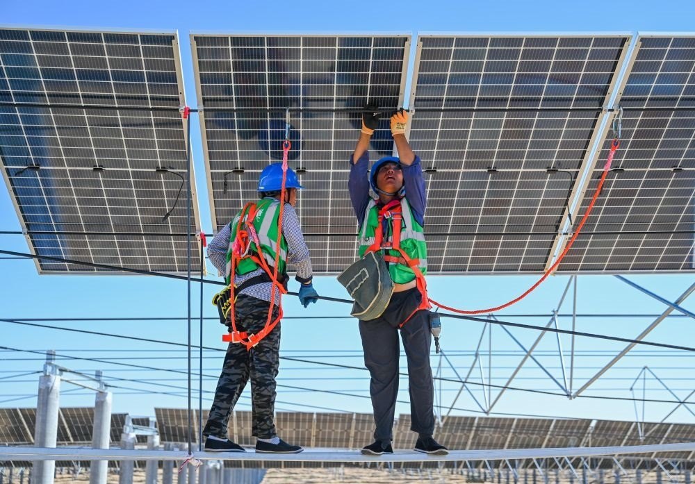 2023年7月22日，工人在位于內蒙古杭錦旗庫布其沙漠億利生態(tài)示范區(qū)的蒙西基地庫布其200萬千瓦光伏治沙項目工地安裝光伏板。新華社記者 劉磊 攝