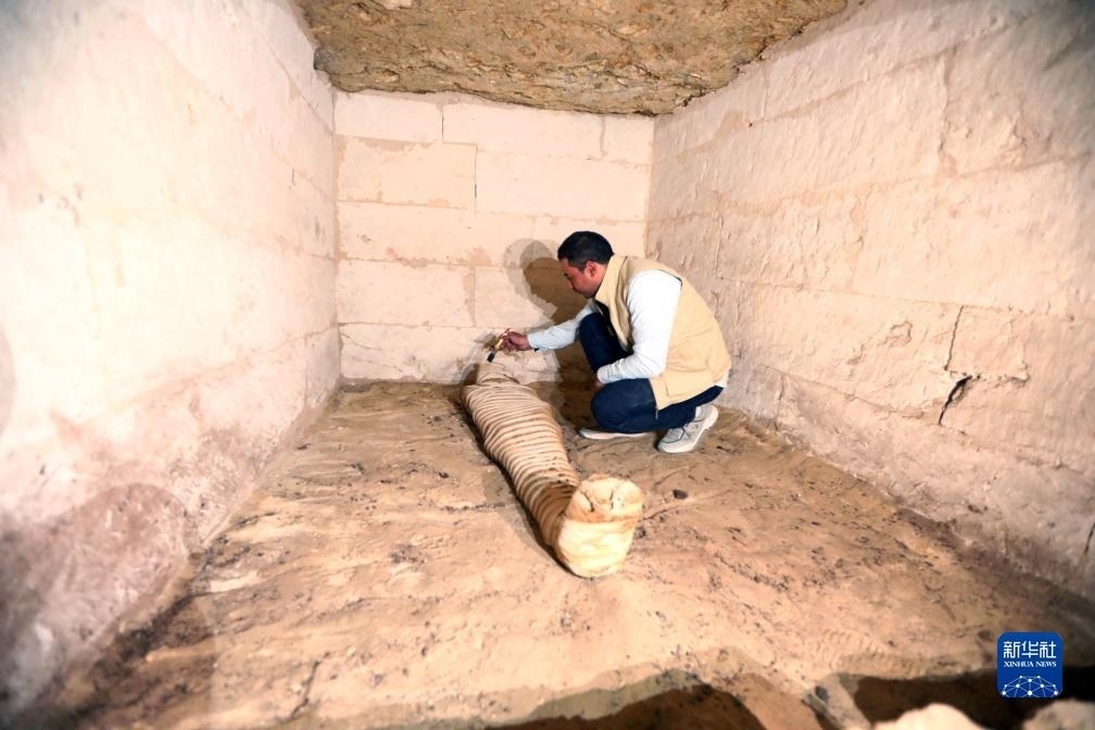 10月15日，在埃及明亞省考古現(xiàn)場(chǎng)，考古人員清理一座石鑿墓中的木乃伊。新華社發(fā)（艾哈邁德·戈馬攝）