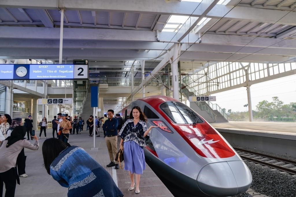 10月17日，在印度尼西亞萬隆德卡魯爾站，乘客在站臺上和雅萬高鐵高速動車組列車合影。