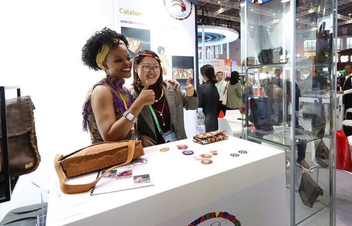 11月6日，一位參觀者（右）在第六屆進(jìn)博會(huì)國(guó)家展南非展臺(tái)試戴傳統(tǒng)首飾。