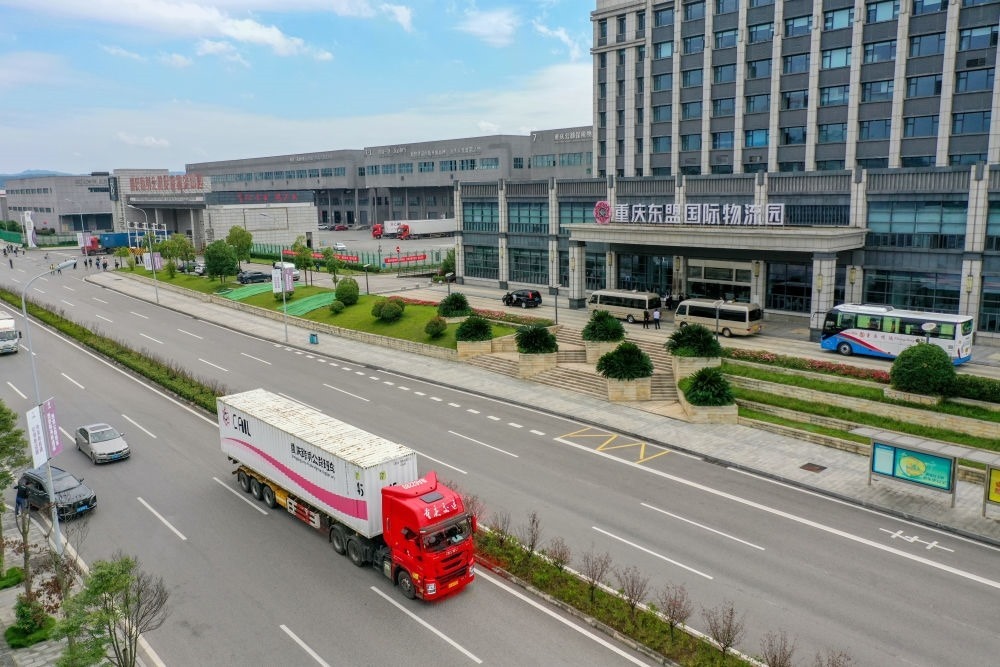 2023年10月11日，滿載筆記本電腦配件、發(fā)電機組件等產(chǎn)品的西部陸海新通道跨境公路班車從重慶南彭公路保稅物流中心駛出，將途經(jīng)廣西憑祥，直達越南（無人機照片）。新華社記者 黃偉 攝