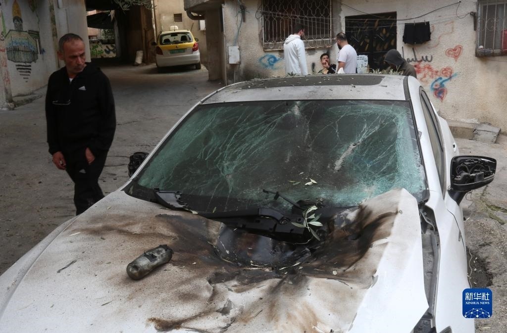 12月17日，在約旦河西岸城市圖勒凱爾姆附近的一處難民營，人們查看在沖突中損毀的車輛。新華社發(fā)（尼達爾·艾仕塔耶?dāng)z）