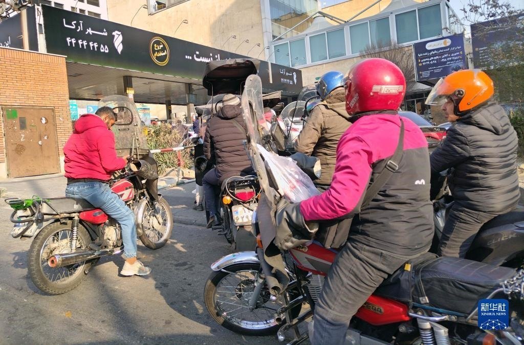 12月18日，摩托車(chē)在伊朗首都德黑蘭的一家加油站外等待加油。新華社記者 沙達(dá)提 攝