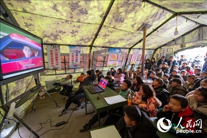 12月22日，在積石山縣大河家鎮(zhèn)大河村安置點(diǎn)，陸軍76集團(tuán)軍某旅搭建的“臨時學(xué)?！眱?nèi)，小朋友正在看動畫片。人民網(wǎng)記者 翁奇羽攝