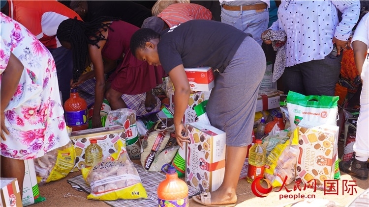 當(dāng)?shù)厣鐓^(qū)家庭領(lǐng)取物資。人民網(wǎng) 張茜攝