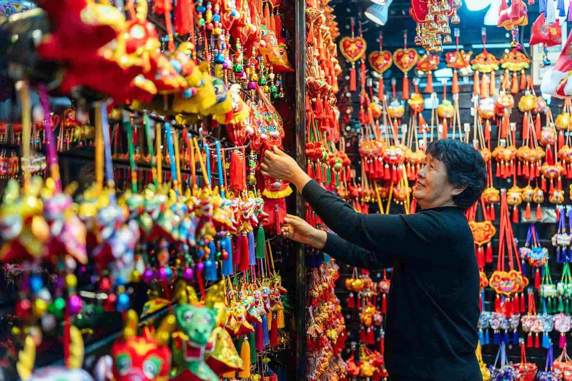 2023年12月11日，金華義烏國際商貿(mào)城，龍年喜慶用品掛滿攤位，顧客正在挑選中。