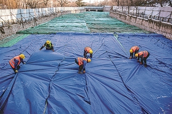 1月3日，房山區(qū)東風(fēng)街道，工人正在修復(fù)的河道內(nèi)給混凝土鋪設(shè)保溫布。