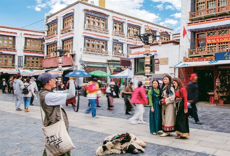 千年八廓街，見證民族團(tuán)結(jié)。2021年7月，習(xí)近平總書記來到位于西藏拉薩老城區(qū)的八廓街，感慨地說：“千年八廓街，是我們各民族建起來的八廓街。各民族文化在這里交流交往交融，我們中華民族的大家庭在這里其樂融融?！眻D為2023年6月13日，游客身著藏裝在八廓街拍照留念。 新華社記者 姜帆/攝