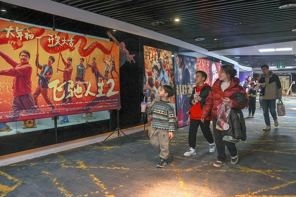 △ 2024年2月16日，在江西贛州一家電影院，觀眾從春節(jié)檔電影的宣傳展板前走過。