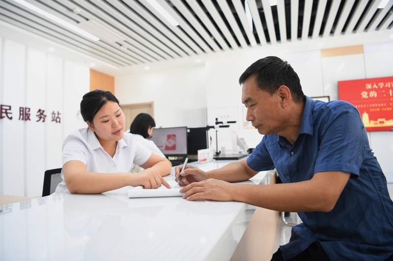 2023年5月23日，河北雄安新區(qū)容東片區(qū)南文營社區(qū)居民（右）在社區(qū)便民服務站辦理業(yè)務。