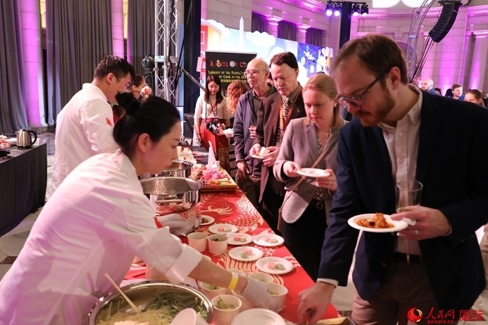 當?shù)貢r間3月7日晚，華盛頓聯(lián)合車站廣場舉行駐美使團“使館主廚挑戰(zhàn)賽”。圖為當?shù)孛癖娫谥袊古_前體驗中國美食。人民網記者 李志偉攝