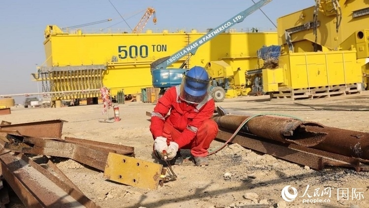 工人正在龍門吊吊裝現(xiàn)場切割金屬件。人民網(wǎng)記者管克江攝