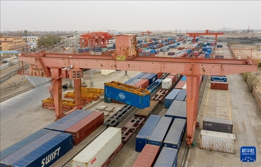 4月21日，二連浩特鐵路口岸龍門吊吊裝中歐班列集裝箱（無人機照片）。 新華社發(fā)（張海峰攝）