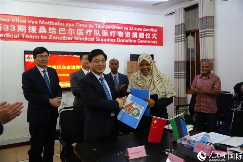 江蘇省蘇北人民醫(yī)院黨委書記束余聲與桑衛(wèi)生部首席秘書哈比巴交換捐贈書。中國援桑醫(yī)療隊供圖