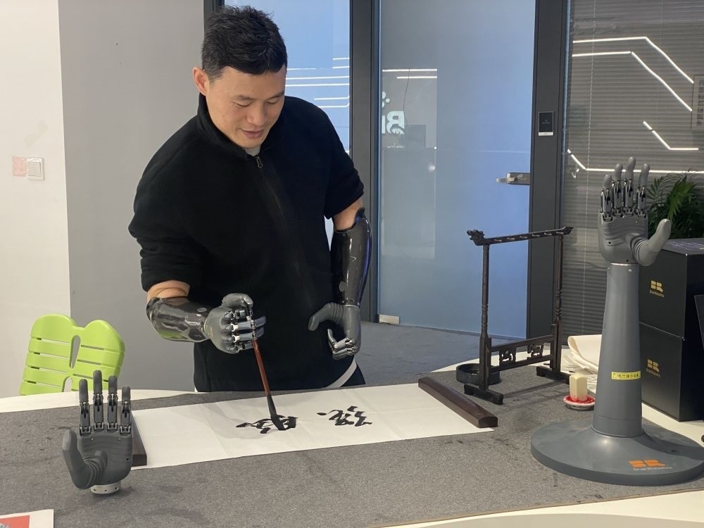 2024年3月29日，在浙江強(qiáng)腦科技有限公司展廳內(nèi)，失去雙手的產(chǎn)品體驗(yàn)官倪敏成依靠智能仿生手寫(xiě)毛筆字。新華社記者 魏一駿 攝