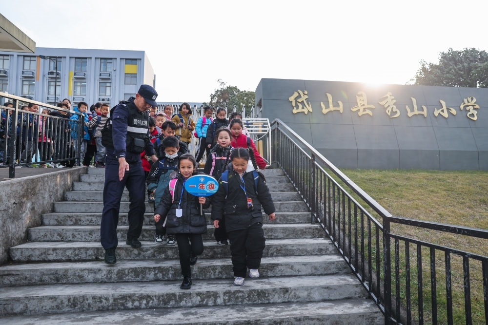 2023年12月20日，秀山派出所民警在秀山小學(xué)放學(xué)時(shí)間參與“護(hù)學(xué)崗”維持秩序，同時(shí)接獨(dú)自放學(xué)的學(xué)生去“民生小鋪”。浙江省舟山市岱山縣公安局秀山派出所聯(lián)合鄉(xiāng)鎮(zhèn)、社區(qū)成立“民生小鋪”，為當(dāng)?shù)鼐用?、外?lái)務(wù)工人員及其子女等服務(wù)，協(xié)助解決外來(lái)務(wù)工人員在工作、生活等方面的矛盾和問(wèn)題，助力鄉(xiāng)鎮(zhèn)基層治理。新華社記者 徐昱 攝