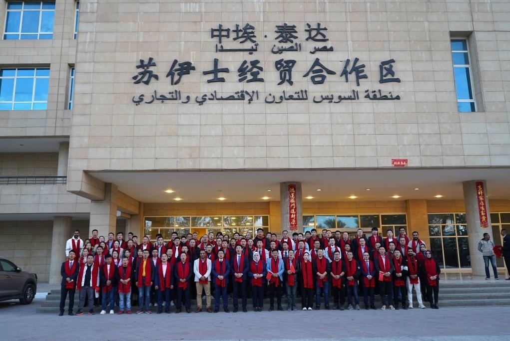 2024年2月11日，在位于埃及蘇伊士省的中?！ぬ┻_蘇伊士經(jīng)貿(mào)合作區(qū)，中埃員工在合作區(qū)辦公大樓前合影拜年。新華社發(fā)（泰達合作區(qū)供圖）