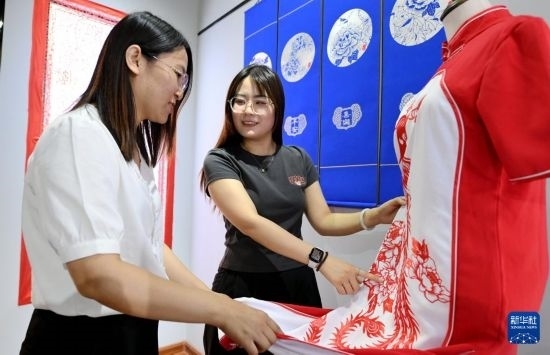 5月31日，在衡水市阜城縣一家剪紙工作室，游客在觀賞帶有剪紙元素的旗袍。