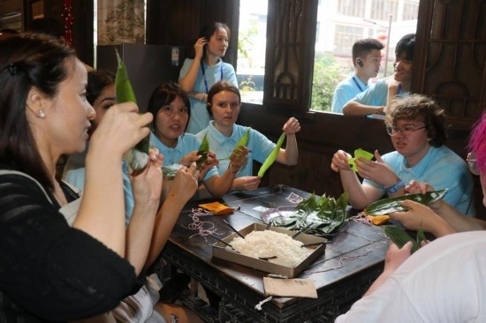 6月9日，美國青年代表在重慶永川松溉古鎮(zhèn)體驗(yàn)包粽子。新華社記者 周思宇 攝