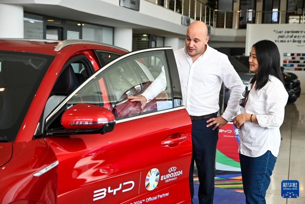 2024年5月29日，在馬耳他比爾基卡拉，馬耳他哈桑-扎米特汽車公司首席執(zhí)行官德古阿拉（左）介紹一輛比亞迪純電動汽車。新華社發(fā)（喬納森·博格 攝）