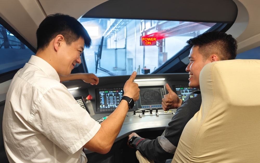 2023年8月25日，在印度尼西亞萬隆的雅萬高鐵德卡魯爾動(dòng)車所內(nèi)，中國(guó)師傅穆振（左）向印尼火車司機(jī)塞蒂亞萬講解動(dòng)車組出庫(kù)前的上電作業(yè)。新華社記者 徐欽 攝