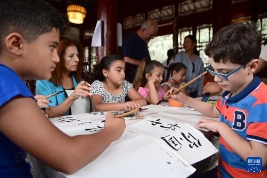 7月4日，在馬耳他桑塔露琪亞市的中國古典園林“靜園”，人們體驗(yàn)中國書法。新華社發(fā)（喬納森·博格 攝）