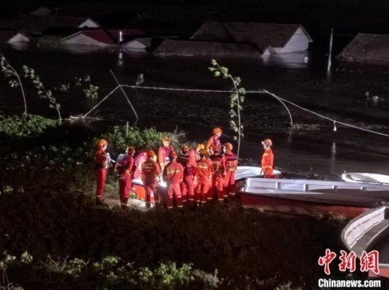  7月6日凌晨3時，在湖南岳陽華容縣團(tuán)洲垸洞庭湖一線堤防，救援人員剛剛完成一次救援任務(wù)，遠(yuǎn)處是被淹的民房。中新社記者 白祖偕 攝