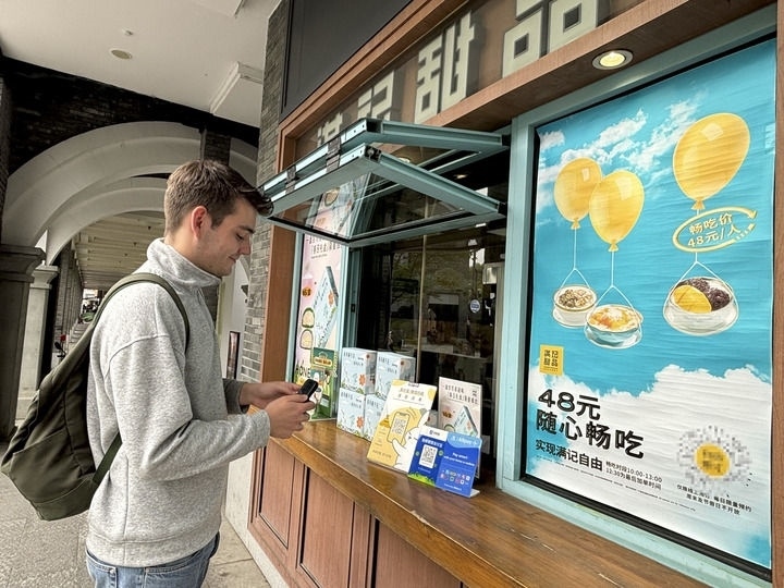 來自德國的留學(xué)生理查德在杭州西湖邊一家商鋪使用支付寶掃碼支付（2024年4月11日攝）。新華社發(fā)