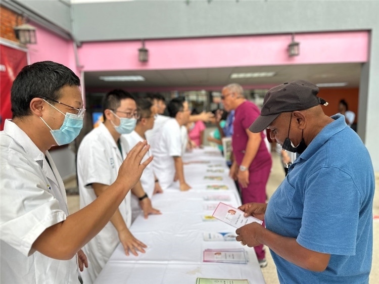 援圭醫(yī)療隊(duì)隊(duì)員們在啟動儀式上為當(dāng)?shù)孛癖姺职l(fā)宣傳手冊。中國援助圭亞那醫(yī)療隊(duì)供圖