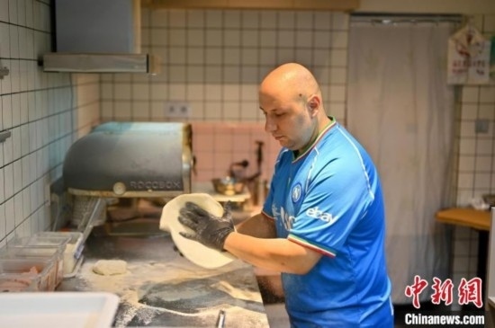 近日，韋榮耀在自家披薩小店內忙活。俞靖 攝