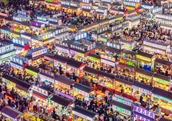 2024年4月21日，人們?cè)诤颖笔≌h小商品夜市品嘗美食（無(wú)人機(jī)照片）。新華社發(fā)（武志偉 攝）