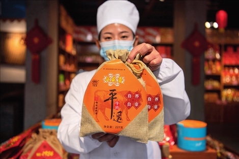 在位于山西省晉中市平遙縣的平遙古城南大街的一家平遙牛肉店內(nèi)，工作人員展示一款牛肉產(chǎn)品（資料照片）楊晨光攝 / 本刊