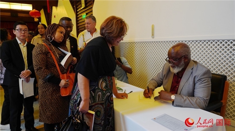 譚哲理在活動(dòng)現(xiàn)場(chǎng)簽名贈(zèng)書。人民網(wǎng) 劉暢攝