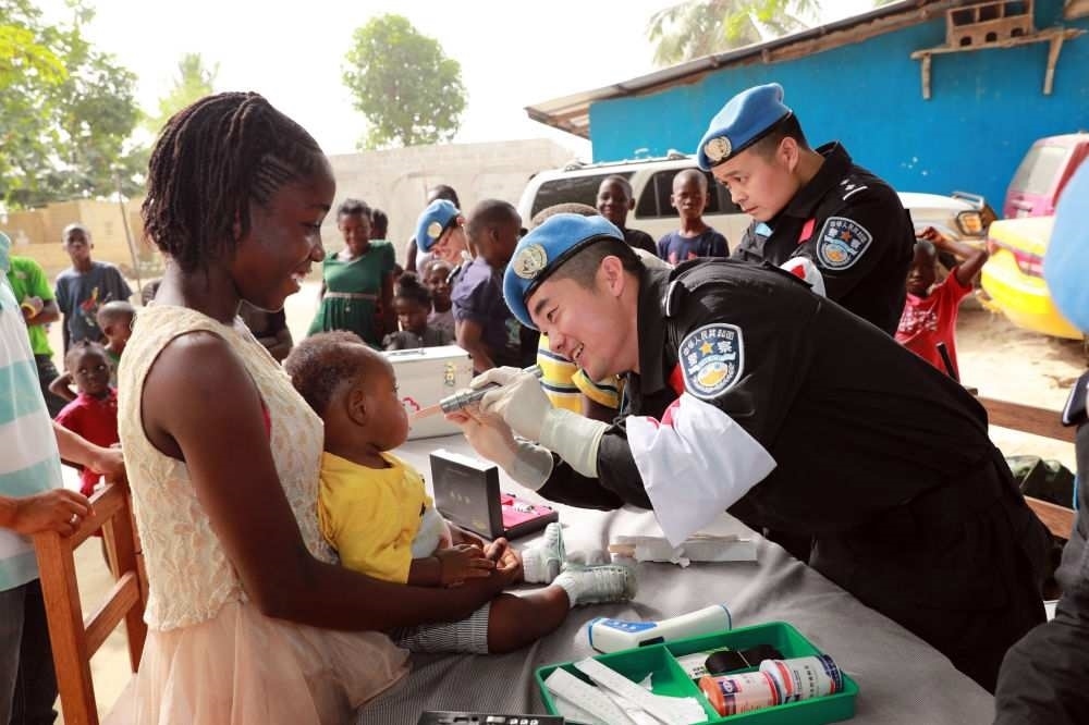 2017年12月28日，在利比里亞蒙羅維亞，中國維和警察防暴隊醫(yī)療人員為兒童做口腔檢查。