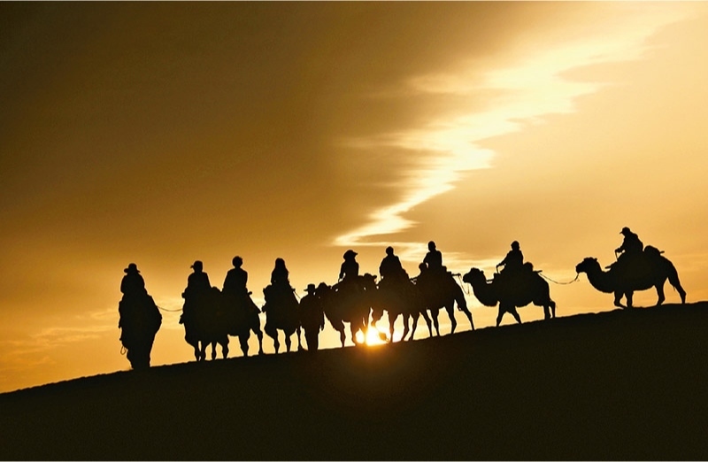 新時代以來，文化和旅游深度融合發(fā)展體制機制不斷健全，成功走出了一條獨具特色的中國旅游發(fā)展之路。圖為2024年9月1日清晨，游客在甘肅省敦煌市鳴沙山月牙泉景區(qū)乘騎駱駝，欣賞大漠風光，體驗絲路風情。 新華社發(fā) 張曉亮/攝