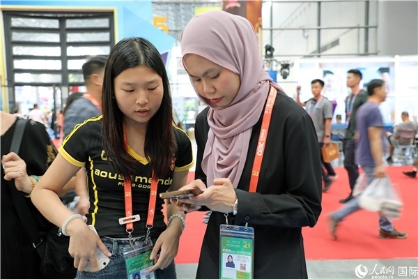 東博會現(xiàn)場，馬來西亞展商在同中方工作人員交談。人民網(wǎng)記者 趙益普攝