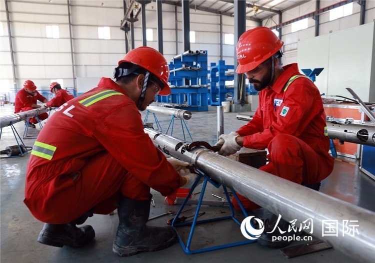 中伊員工共同在檢修鉆井設(shè)備。人民網(wǎng)記者管克江攝