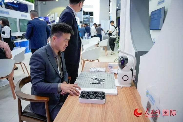 觀眾在中國移動國際有限公司展臺體驗智慧圍棋機器人。人民網(wǎng) 塔里克·易卜拉欣攝