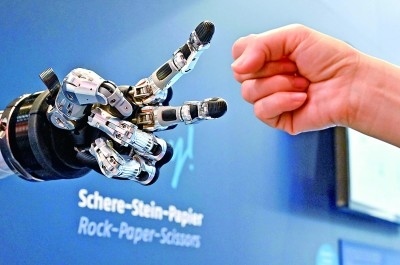 在德國漢諾威工博會上，參觀者與一款智能機器人進行“石頭剪子布”游戲。新華社發(fā)