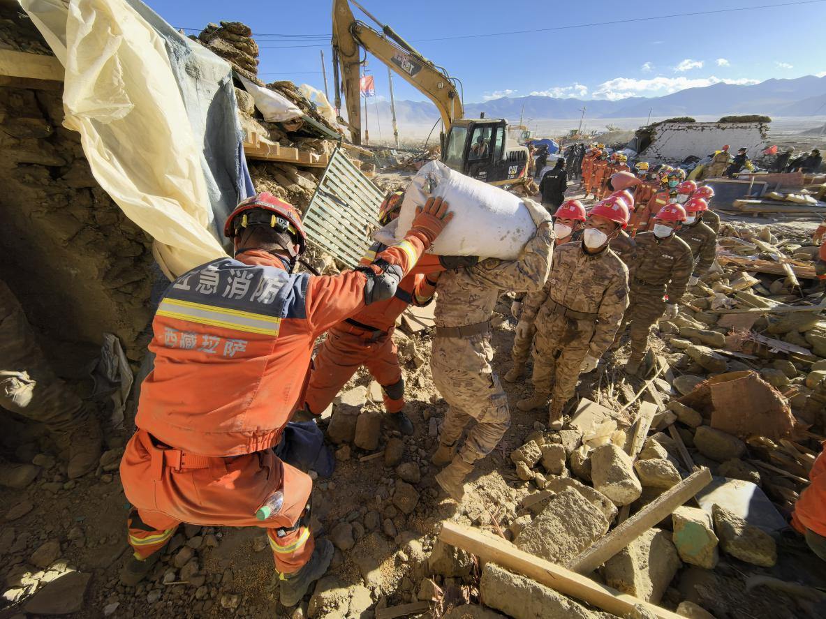 1月11日，定日縣長所鄉(xiāng)古榮村，應(yīng)急消防等救援人員排隊(duì)接力搶運(yùn)掩埋在倒塌房屋下的群眾財(cái)物。人民日報(bào)記者楊翹楚攝