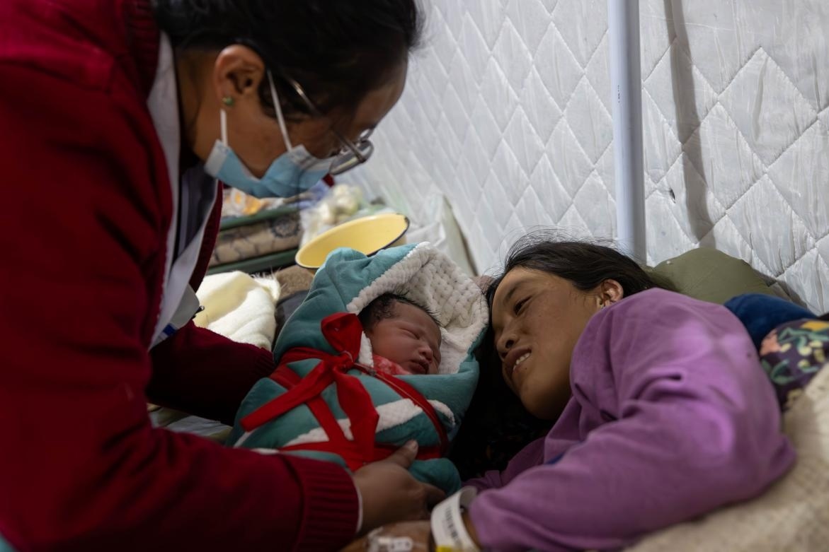 1月10日，定日縣中心醫(yī)院的婦產(chǎn)科醫(yī)生悉心照看一位母親和她懷里的新生兒。人民日報(bào)記者張武軍攝