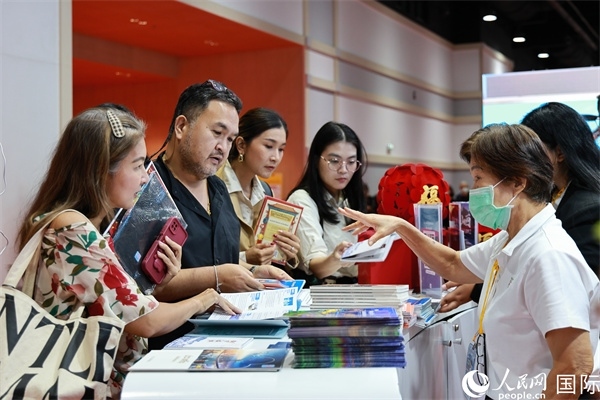 外國(guó)觀眾在中國(guó)展臺(tái)仔細(xì)閱讀赴華旅游介紹，向工作人員咨詢關(guān)于中國(guó)美食和景點(diǎn)的詳細(xì)信息。人民網(wǎng)記者 白元琪攝